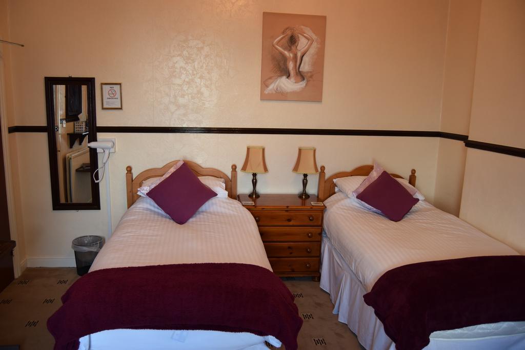 A classic twin room with two single beds, warm wood and lamplight